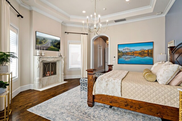 6615 Bluffview Dr, Frisco, TX 75034 - bedroom featuring a tray ceiling, arched walkways, wood finished floors, a high end fireplace, and crown molding