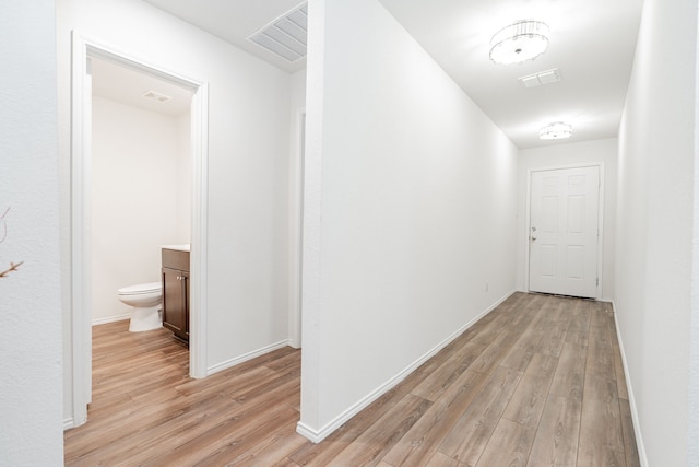 corridor featuring visible vents, baseboards, and light wood-style floors
