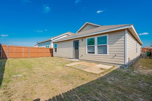 back of property featuring central air condition unit, fence, and a lawn