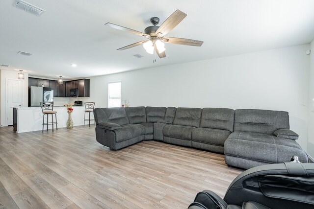 living room featuring light wood-style flooring, ceiling fan, and visible vents