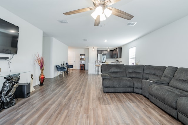 living room with visible vents, ceiling fan, and light wood finished floors