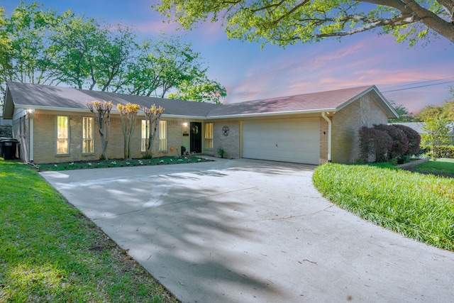 ranch-style home featuring a yard, a garage, concrete driveway, and brick siding