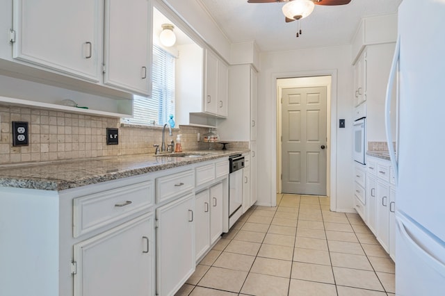 kitchen featuring white appliances, white cabinetry, light tile patterned flooring, ceiling fan, and a sink