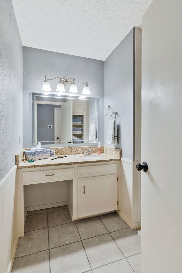 bathroom featuring a textured ceiling, vanity, a textured wall, and tile patterned flooring