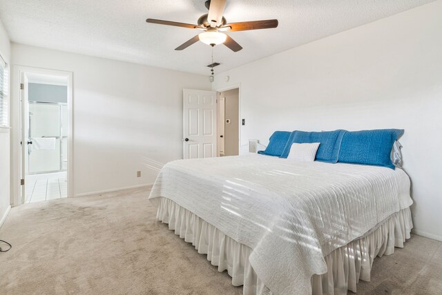 bedroom featuring connected bathroom, a textured ceiling, visible vents, light carpet, and baseboards