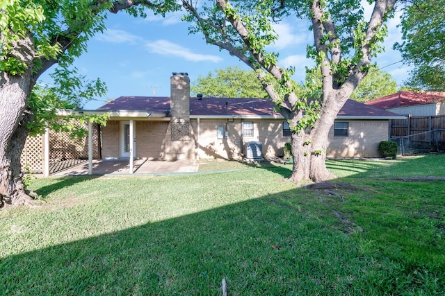 back of property with fence, a patio, a lawn, and a chimney