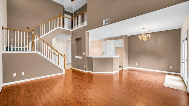 908 Englewood Ln, Plano, TX 75025 - unfurnished living room featuring stairway, wood finished floors, a chandelier, and a towering ceiling