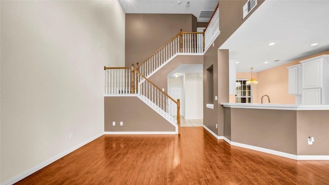 908 Englewood Ln, Plano, TX 75025 - unfurnished living room featuring stairs, wood finished floors, a towering ceiling, and recessed lighting