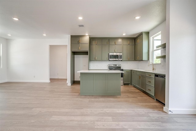 kitchen featuring stainless steel appliances, tasteful backsplash, a kitchen island, visible vents, and green cabinets