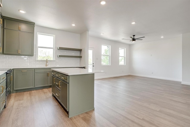 kitchen with ceiling fan, a kitchen island, electric range, green cabinets, and light wood finished floors