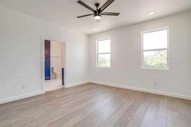 interior space with baseboards, light wood finished floors, ensuite bathroom, and ceiling fan