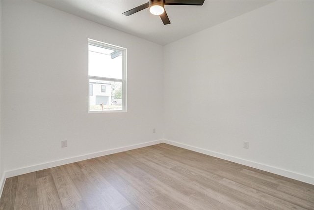 spare room featuring a ceiling fan, baseboards, and light wood finished floors