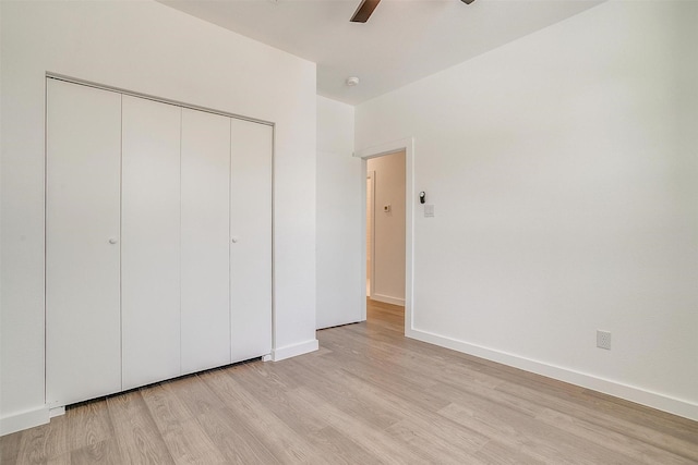 unfurnished bedroom with a ceiling fan, baseboards, light wood finished floors, and a closet