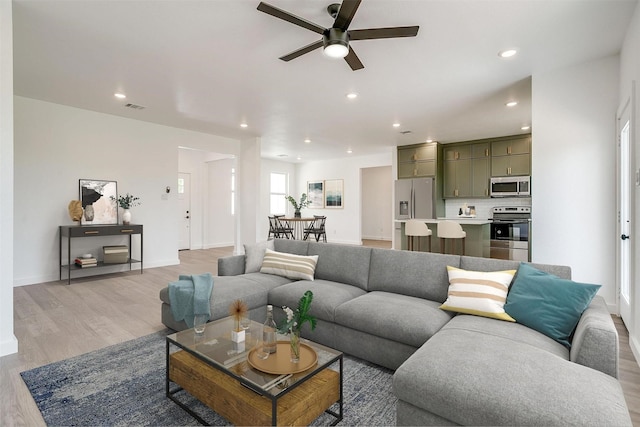 living area featuring ceiling fan, light wood-style floors, recessed lighting, baseboards, and visible vents