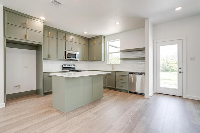 kitchen with tasteful backsplash, stainless steel appliances, light wood finished floors, and visible vents