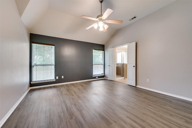 spare room with a ceiling fan, vaulted ceiling, visible vents, wood finished floors, and baseboards