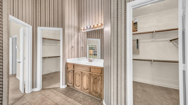 8708 Tangleridge Dr, Fort Worth, TX 76123 - bathroom featuring vanity, a walk in closet, tile patterned flooring, and wallpapered walls