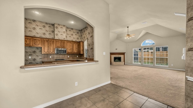 8708 Tangleridge Dr, Fort Worth, TX 76123 - kitchen with refrigerator, stainless steel microwave, carpet, a tiled fireplace, and ceiling fan