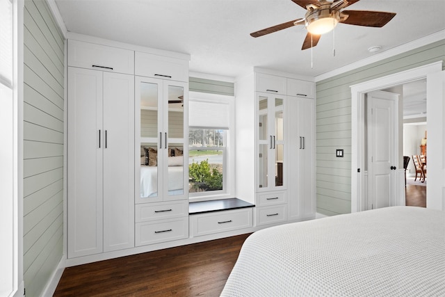 bedroom with dark wood-type flooring, ceiling fan, crown molding, and wooden walls