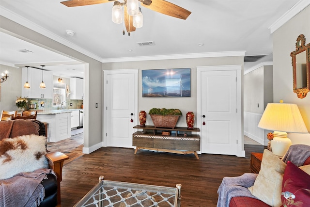 living room with baseboards, ornamental molding, dark wood-type flooring, visible vents, and ceiling fan