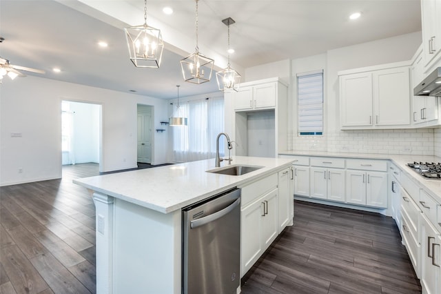 kitchen with under cabinet range hood, dark wood-style flooring, a sink, stainless steel appliances, and backsplash