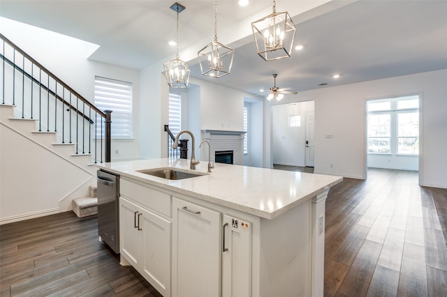 kitchen featuring a brick fireplace, dishwasher, a sink, open floor plan, and dark wood-style floors