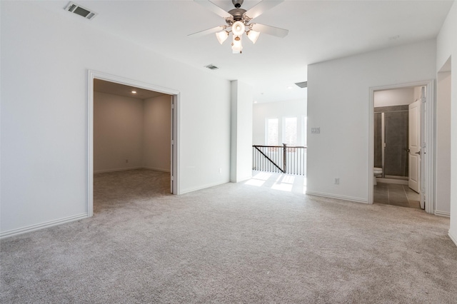 carpeted empty room featuring visible vents, ceiling fan, and baseboards