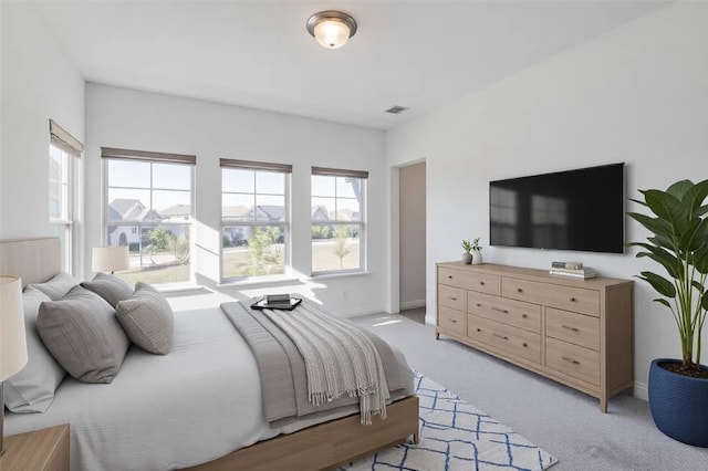 bedroom with baseboards, visible vents, multiple windows, and light colored carpet