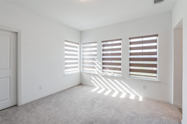 carpeted spare room with visible vents, baseboards, and plenty of natural light