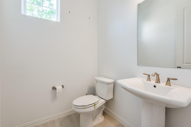 half bathroom with toilet, a sink, and baseboards