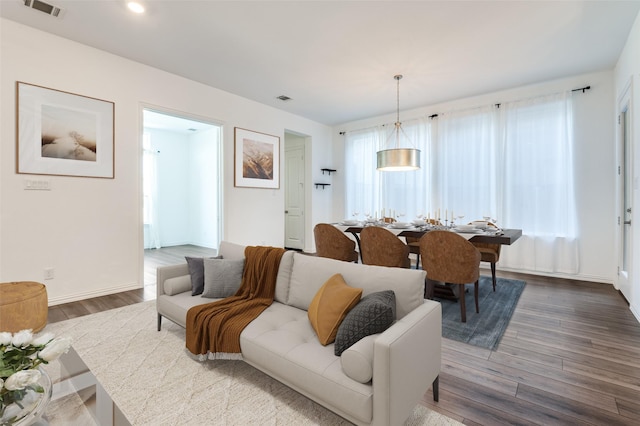 living room featuring visible vents, baseboards, recessed lighting, and wood finished floors