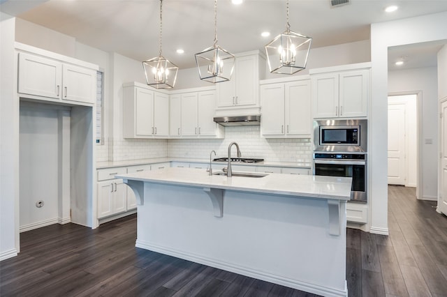 kitchen featuring white cabinets, appliances with stainless steel finishes, a chandelier, dark wood-type flooring, and backsplash