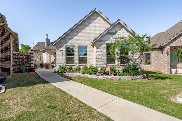 view of front of house with a front yard, stone siding, and brick siding