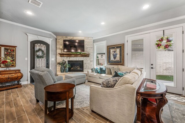 living area with a wealth of natural light, a fireplace, visible vents, and crown molding