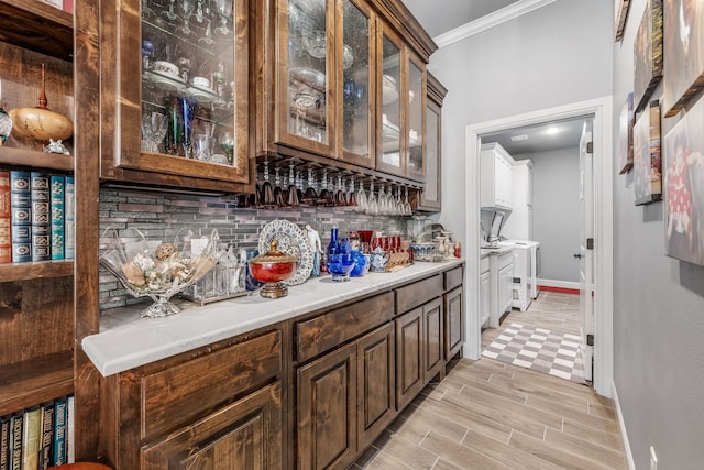 bar featuring tasteful backsplash, ornamental molding, baseboards, and bar