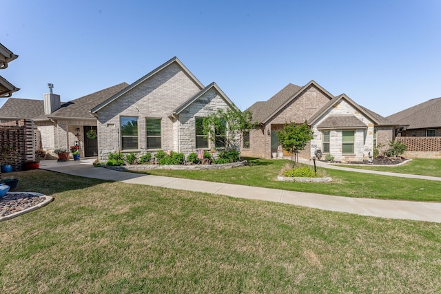 view of front of house featuring roof with shingles, a front yard, brick siding, and stone siding