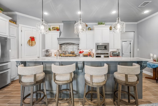 kitchen featuring custom exhaust hood, crown molding, visible vents, decorative backsplash, and stainless steel appliances