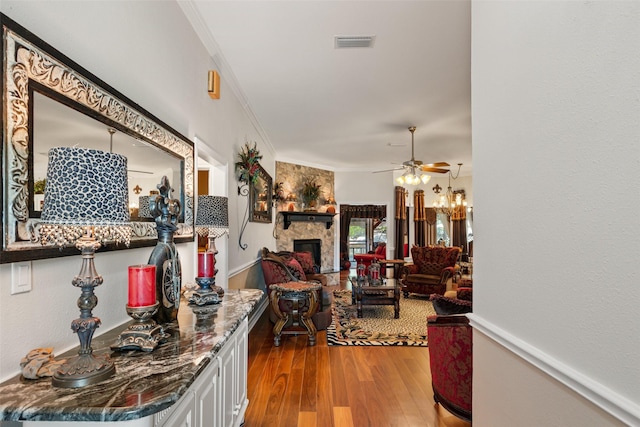 1412 Conejos Ct, Granbury, TX 76048 - living area with a ceiling fan, a stone fireplace, visible vents, wood finished floors, and ornamental molding