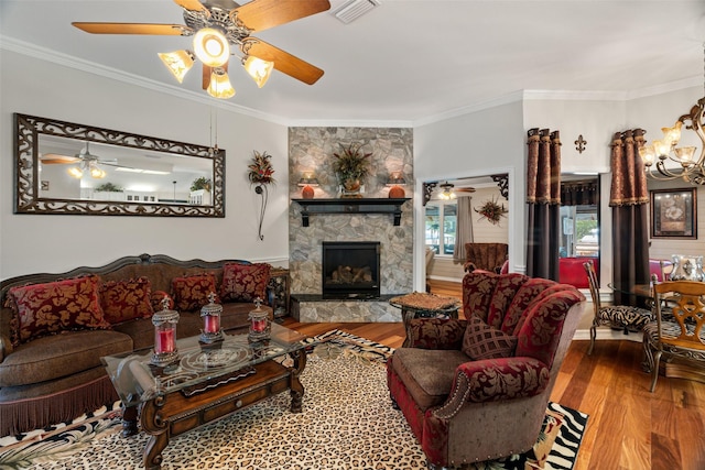 1412 Conejos Ct, Granbury, TX 76048 - living room featuring crown molding, a stone fireplace, ceiling fan with notable chandelier, wood finished floors, and visible vents