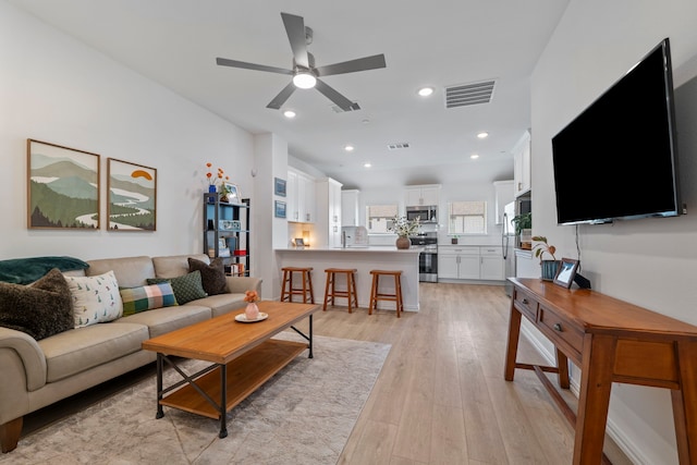 living room featuring light wood finished floors, ceiling fan, visible vents, and recessed lighting