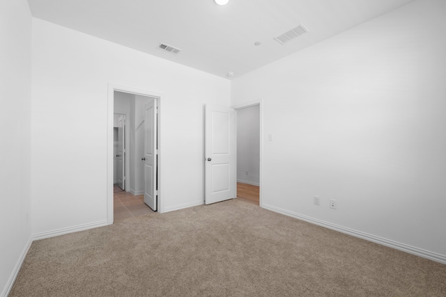 unfurnished bedroom with visible vents, baseboards, and light colored carpet