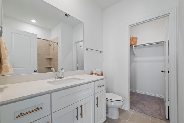 bathroom with walk in shower, toilet, a spacious closet, vanity, and tile patterned flooring