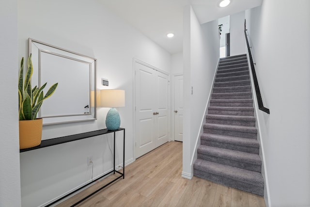 stairs with wood finished floors, baseboards, and recessed lighting