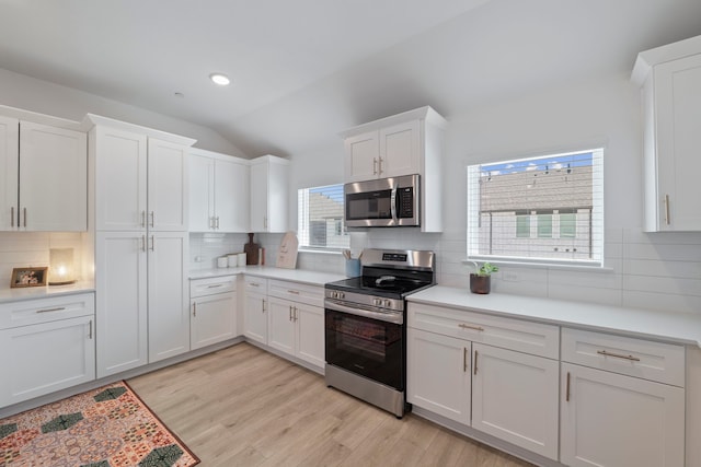 kitchen with backsplash, white cabinetry, and stainless steel appliances