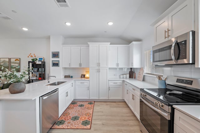 kitchen featuring visible vents, a sink, light countertops, a peninsula, and stainless steel appliances