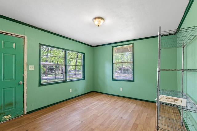 empty room featuring light wood-type flooring, baseboards, and ornamental molding