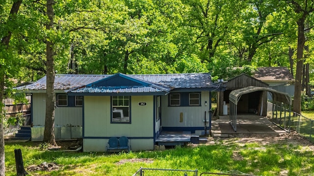 view of front of property with a carport, metal roof, and fence