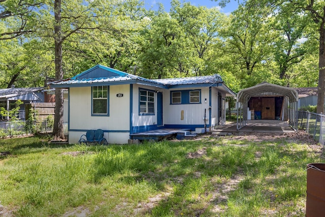 view of front of home with a detached carport, fence, and metal roof