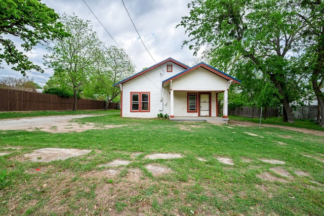 view of front of home with a front yard, a porch, and fence