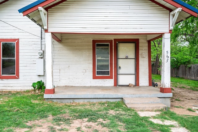 doorway to property featuring a porch and fence